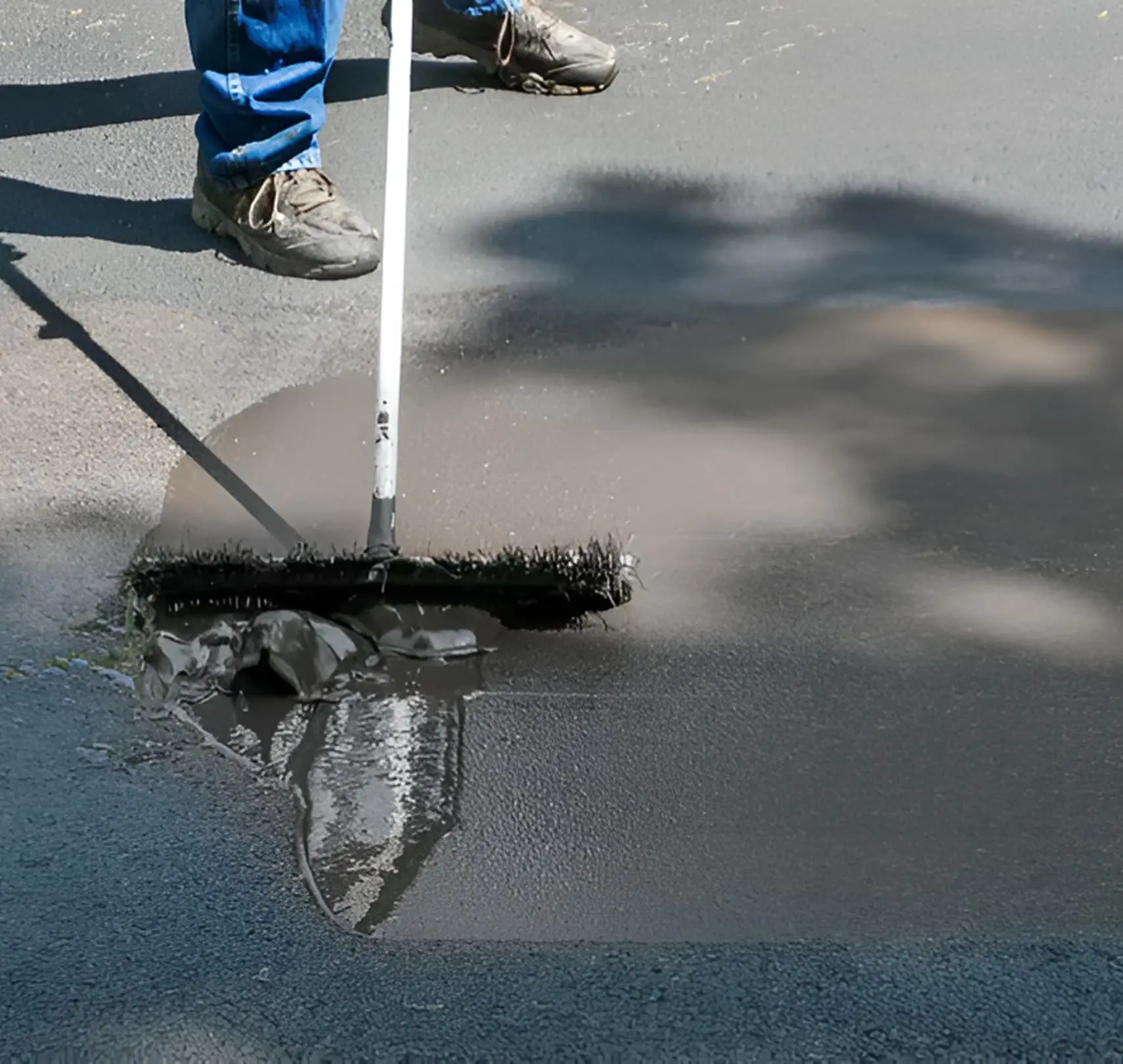 Person spreading asphalt on road surface.