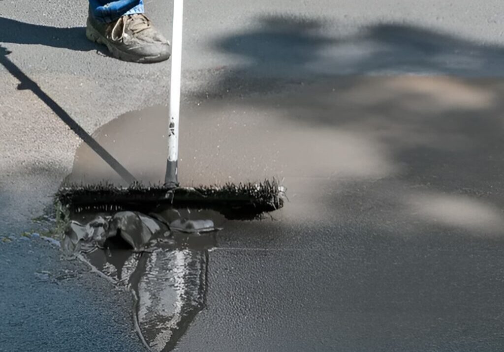 Person spreading asphalt on road surface.
