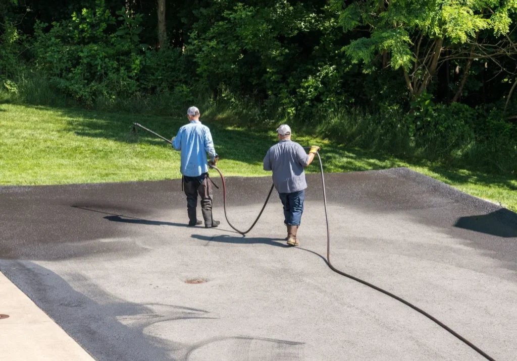 asphalt+driveway+installation+trinity+nc-1920w Workers sealing a driveway with hoses.